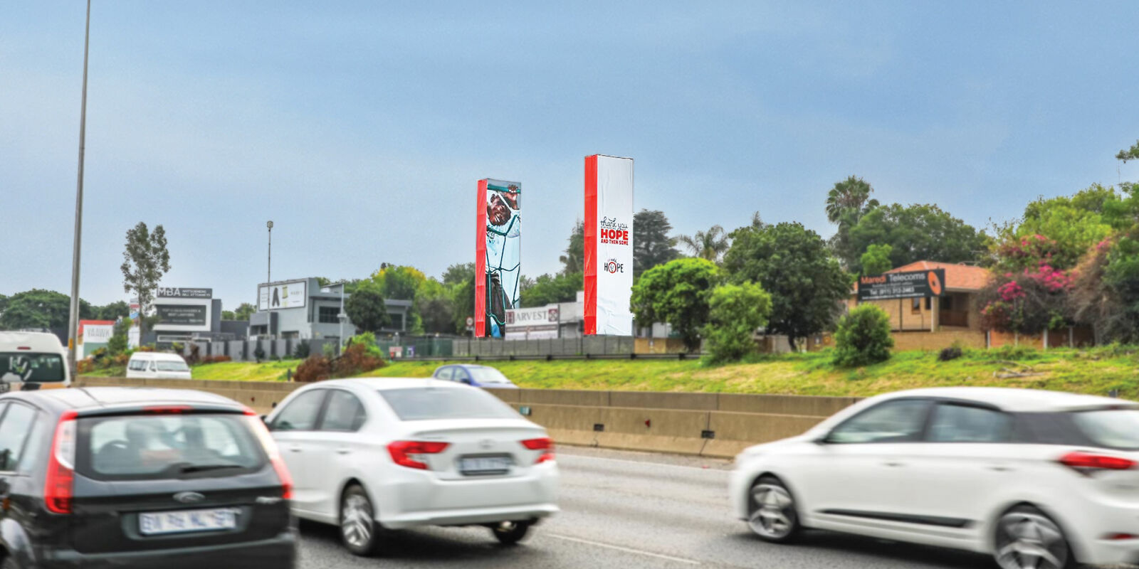 Printed tower banners for a Hope campaign beside a highway